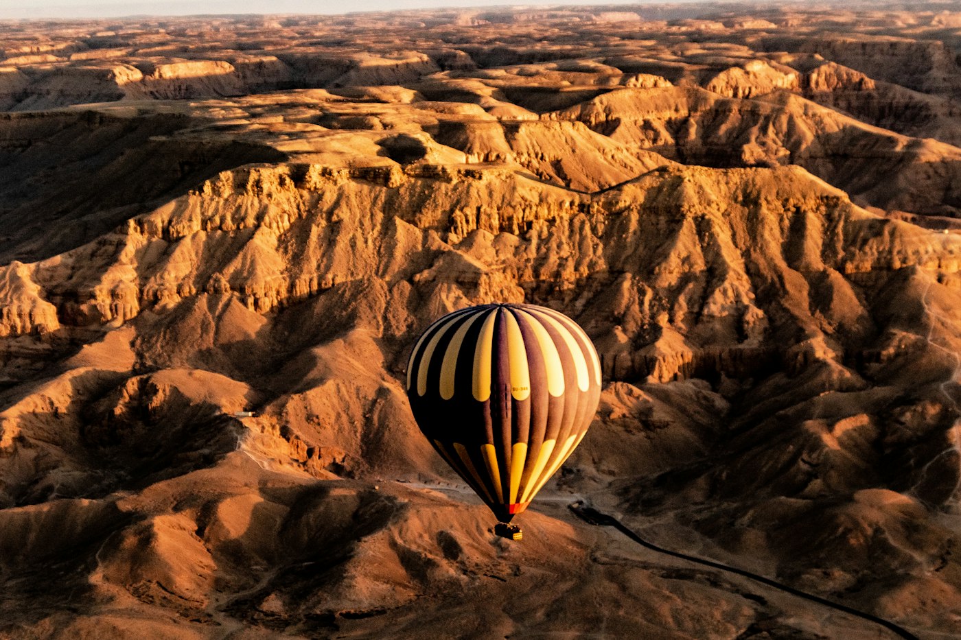 Hot air balloon floating over the hills of the Luxor West Bank at sunrise